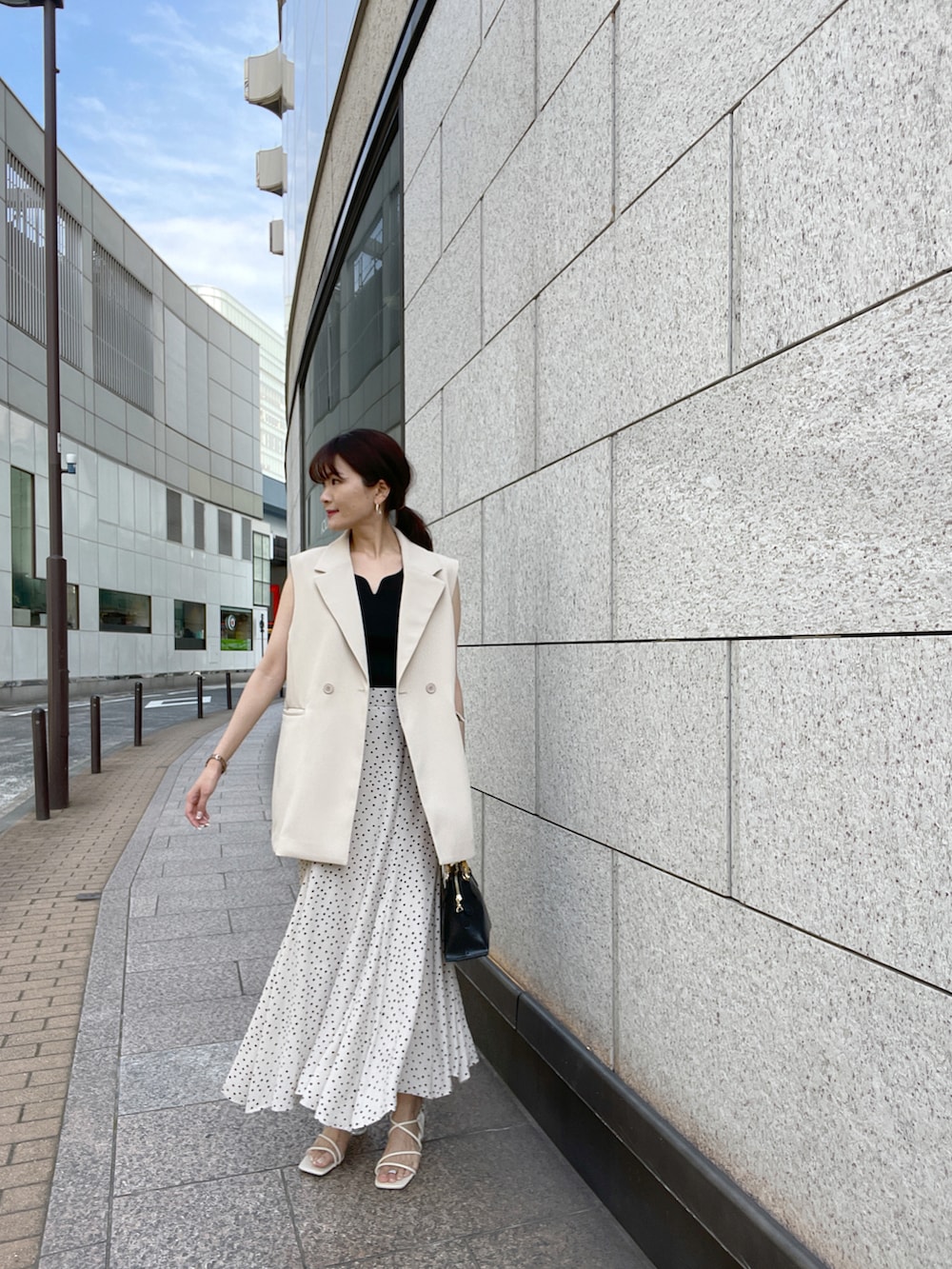 ブラック系のニット/セーター、ホワイト系のジャケット/アウター、ベージュ系のスカートを着用したレディースの春コーディネートの3枚目の写真