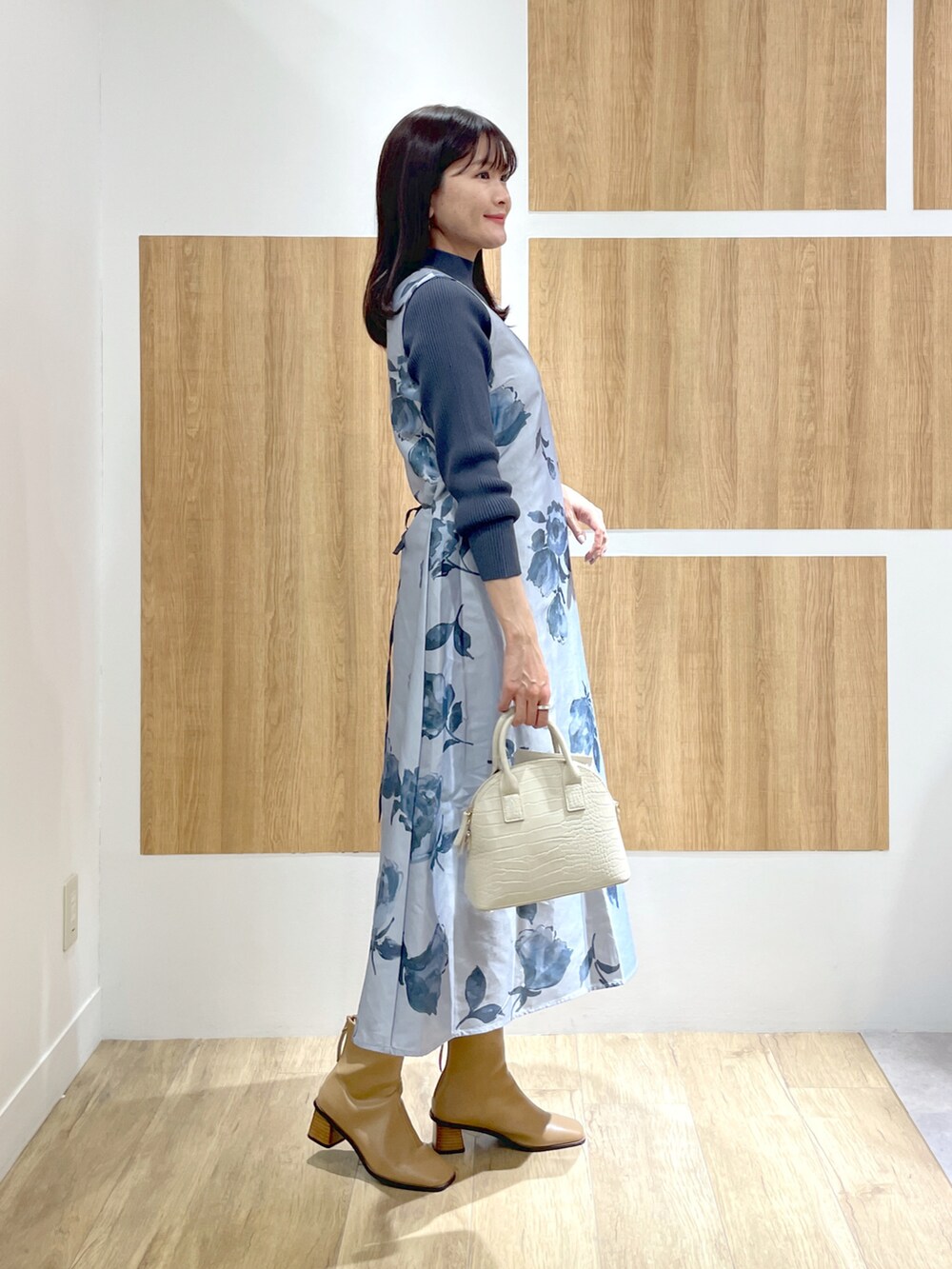 ブルー系のワンピース、ホワイト系のショルダーバッグ、グレー系のパンプスを着用したレディースの冬コーディネートの2枚目の写真