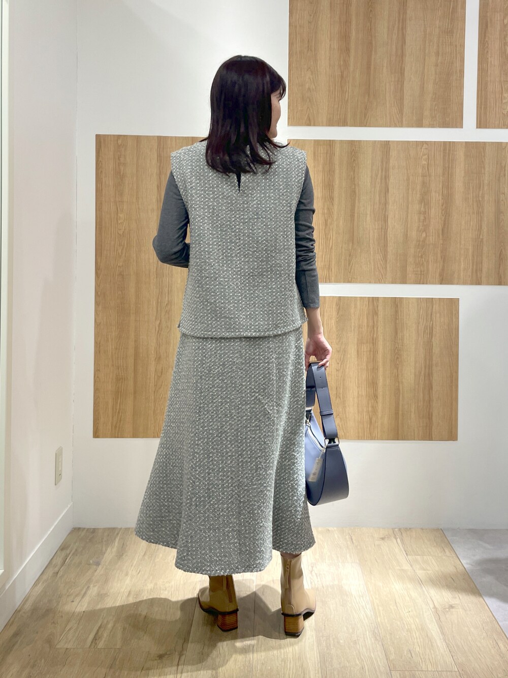 グレー系のTシャツ/カットソー、グレー系のスカート、ブルー系のショルダーバッグを着用したレディースの冬コーディネートの3枚目の写真