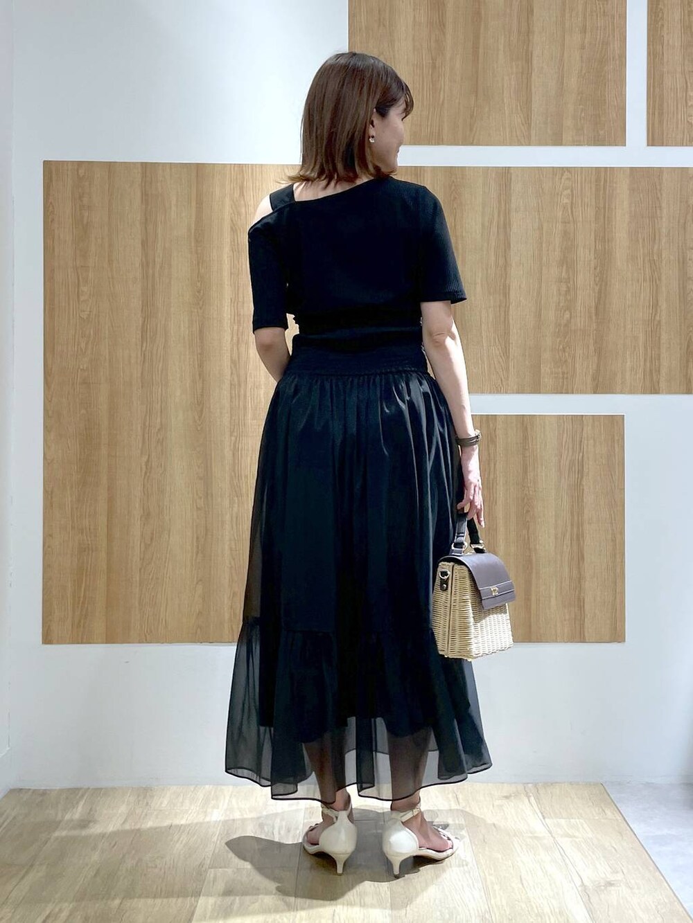 ブラウン系のかごバッグ、ホワイト系のサンダル、ブラック系のスカートを着用したレディースの夏コーディネートの4枚目の写真