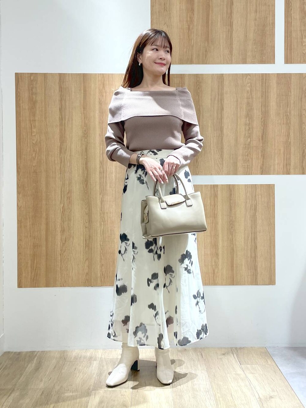 ホワイト系のブーツ、ベージュ系のハンドバッグ、ホワイト系のスカートを着用したレディースの冬コーディネートの2枚目の写真
