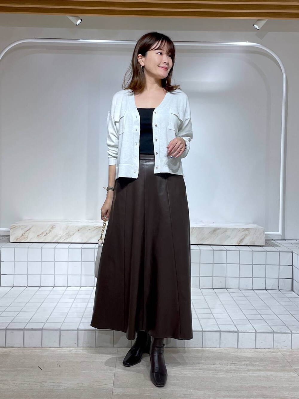 ブラウン系のブーツ、ブラック系のキャミソール、ホワイト系のカーディガン/ボレロを着用したレディースの秋コーディネートの2枚目の写真