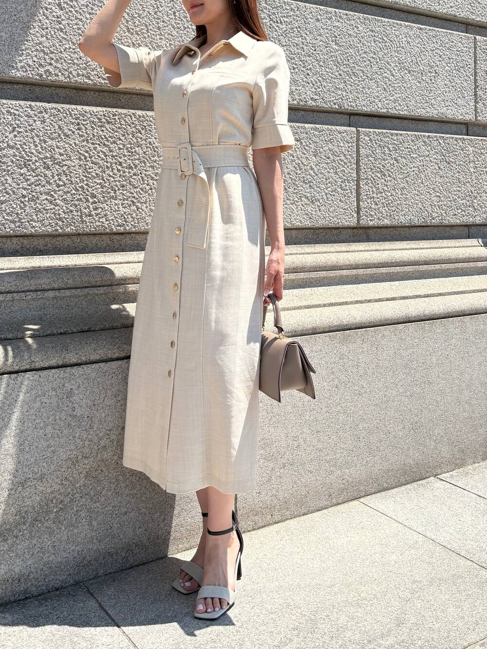 ブラック系のサンダル、ベージュ系のワンピースを着用したレディースの春コーディネートの2枚目の写真