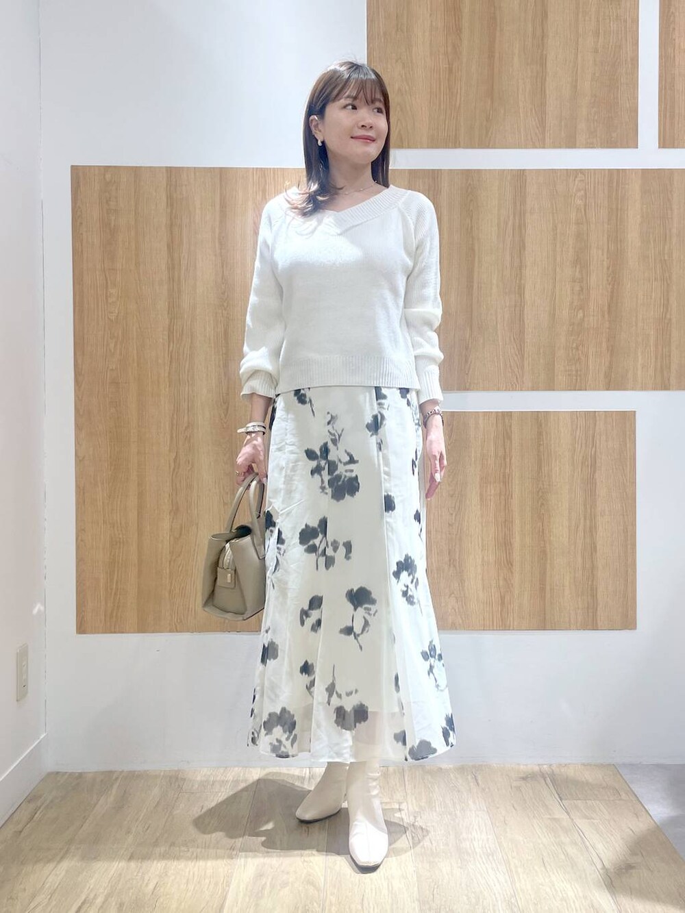 ホワイト系のブーツ、ベージュ系のハンドバッグ、ホワイト系のスカートを着用したレディースの冬コーディネートの2枚目の写真