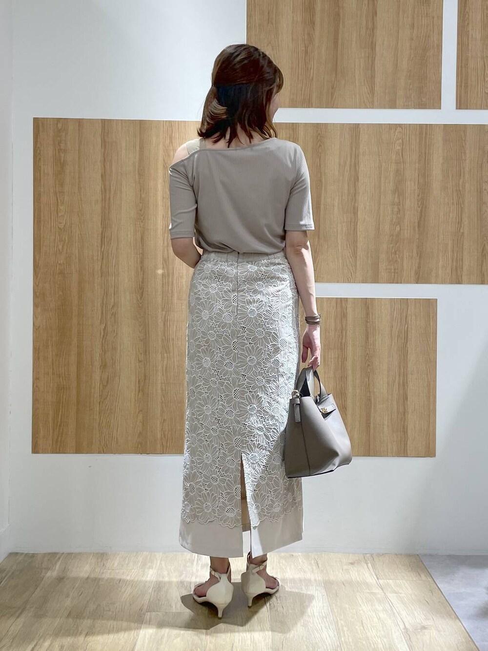 ホワイト系のサンダル、ベージュ系のハンドバッグ、ベージュ系のスカートを着用したレディースの夏コーディネートの4枚目の写真