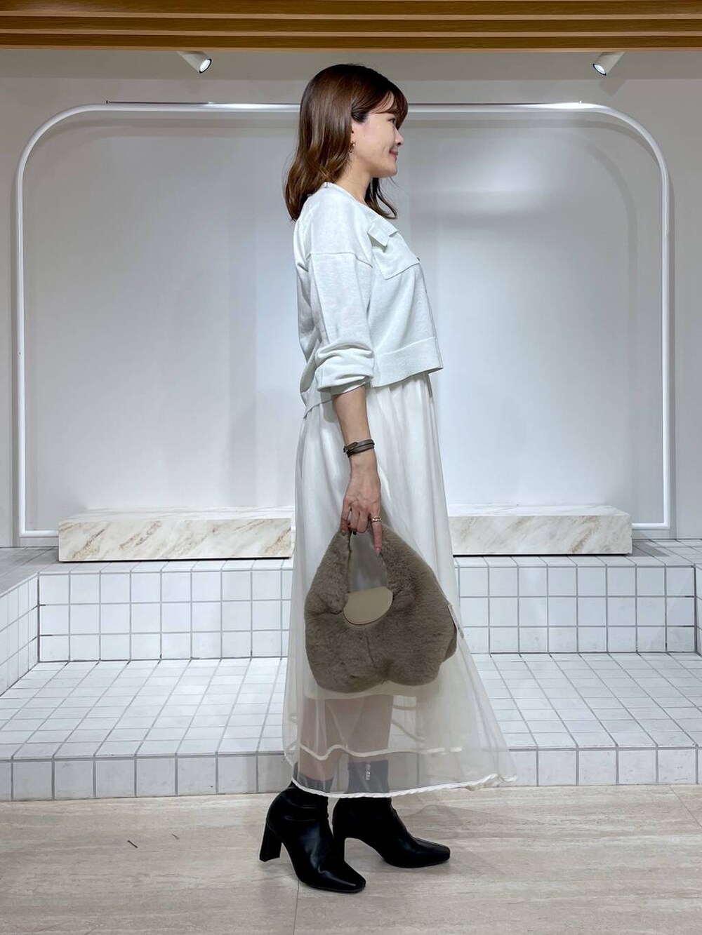 ホワイト系のスカート、ブラック系のブーツ、ホワイト系のカーディガン/ボレロを着用したレディースの秋コーディネートの3枚目の写真