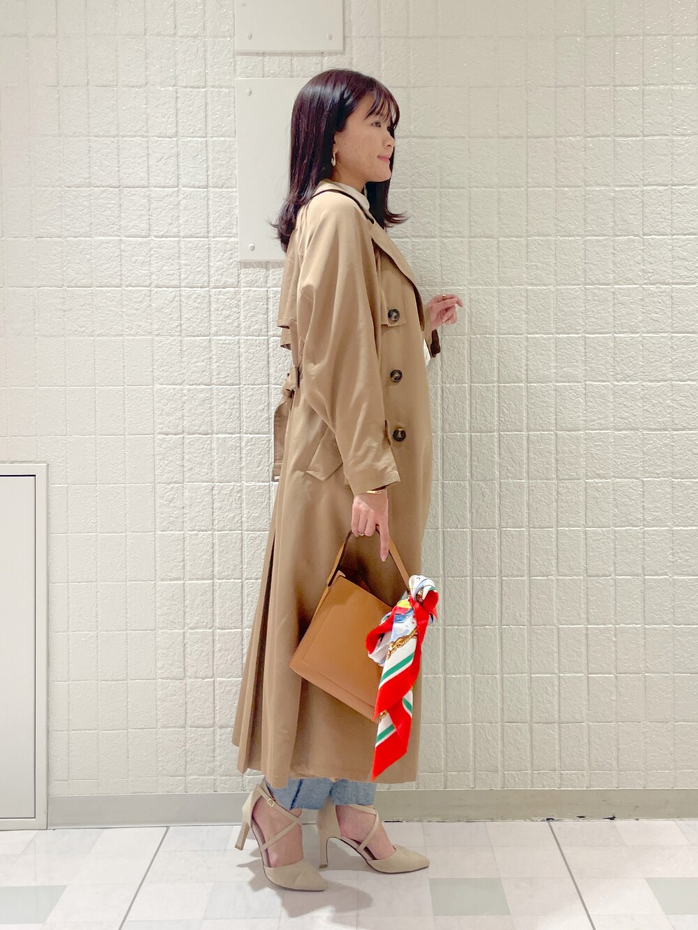 ベージュ系のトレンチコート、ホワイト系のシャツ/ブラウス、ブルー系のデニムパンツを着用したレディースの冬コーディネートの2枚目の写真