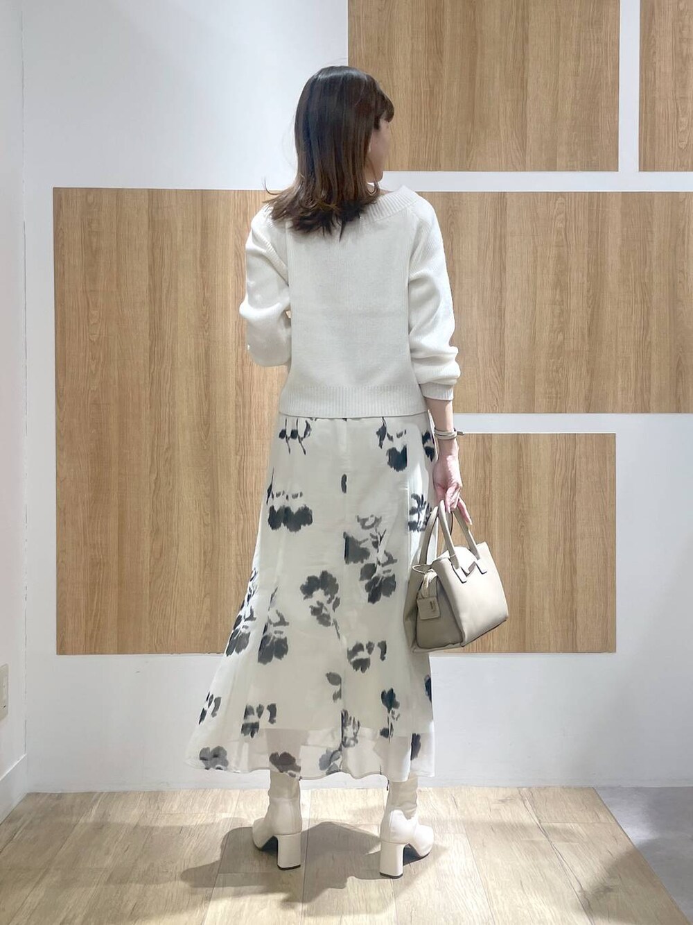 ホワイト系のブーツ、ベージュ系のハンドバッグ、ホワイト系のスカートを着用したレディースの冬コーディネートの4枚目の写真