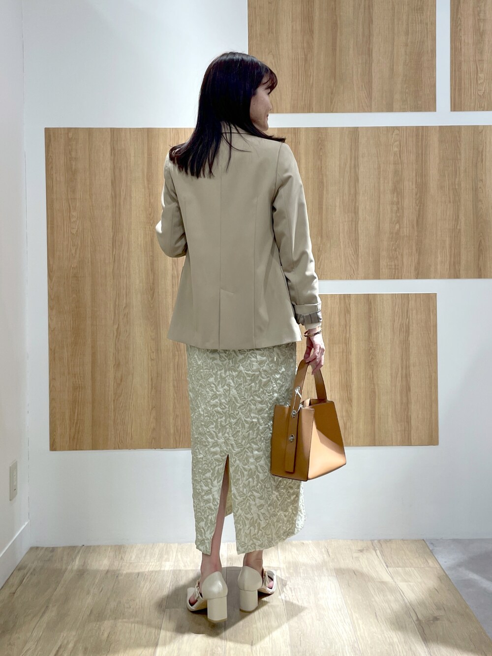 ベージュ系のテーラードジャケット、ホワイト系のニット/セーター、グリーン系のスカートを着用したレディースの冬コーディネートの3枚目の写真