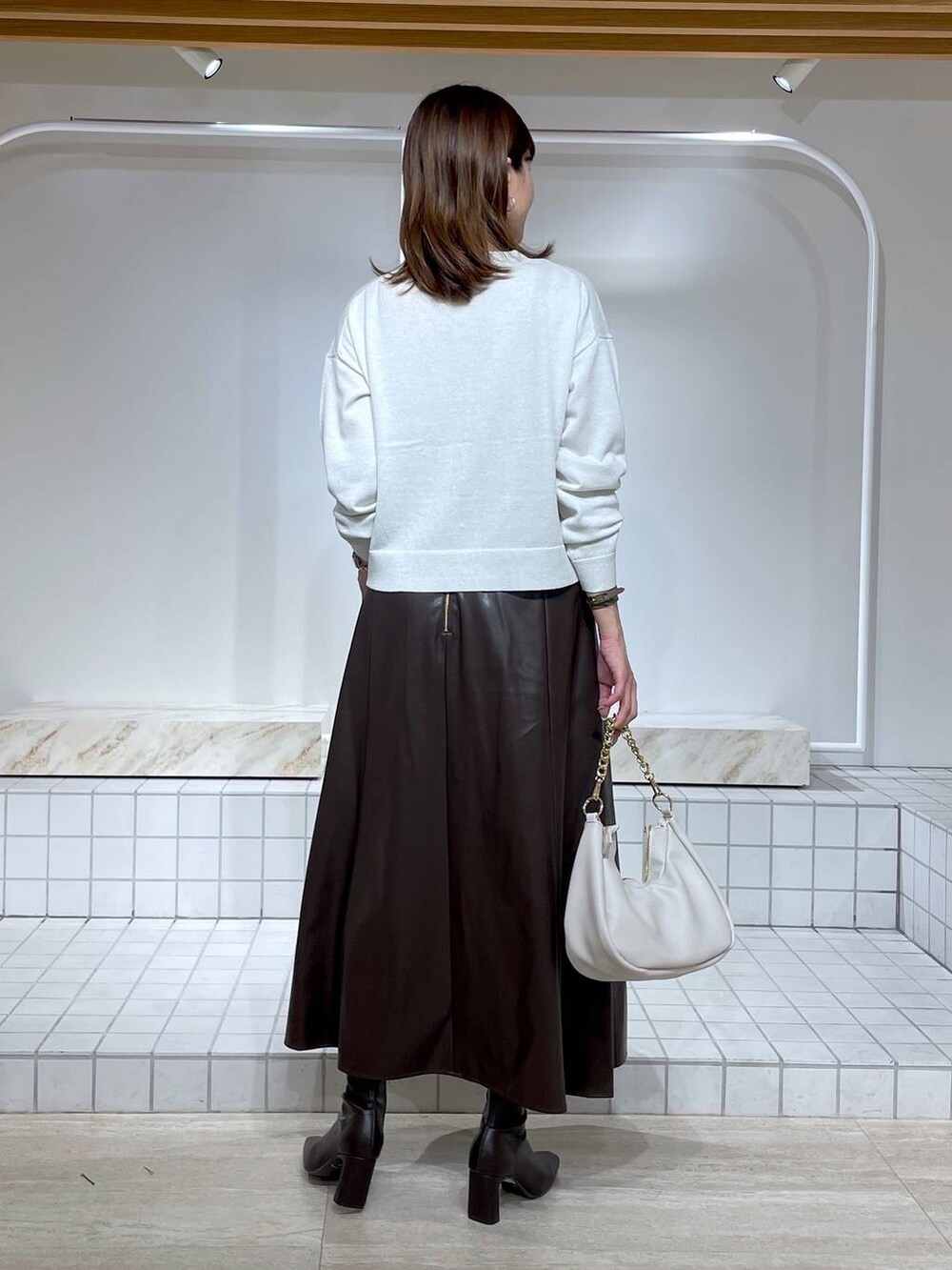 ブラウン系のブーツ、ブラック系のキャミソール、ホワイト系のカーディガン/ボレロを着用したレディースの秋コーディネートの4枚目の写真