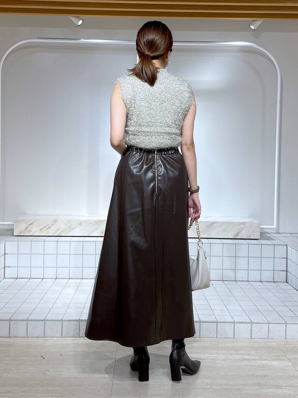 ブラウン系のブーツ、グレー系のニット/セーター、ホワイト系のショルダーバッグを着用したレディースの秋コーディネートの4枚目の写真