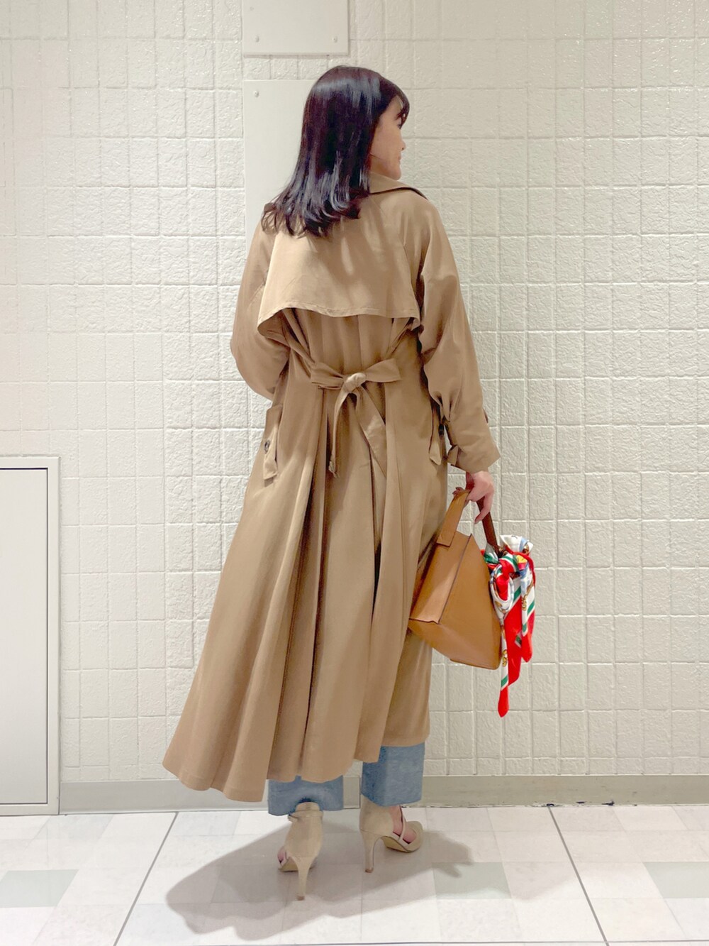 ベージュ系のトレンチコート、ホワイト系のシャツ/ブラウス、ブルー系のデニムパンツを着用したレディースの冬コーディネートの3枚目の写真