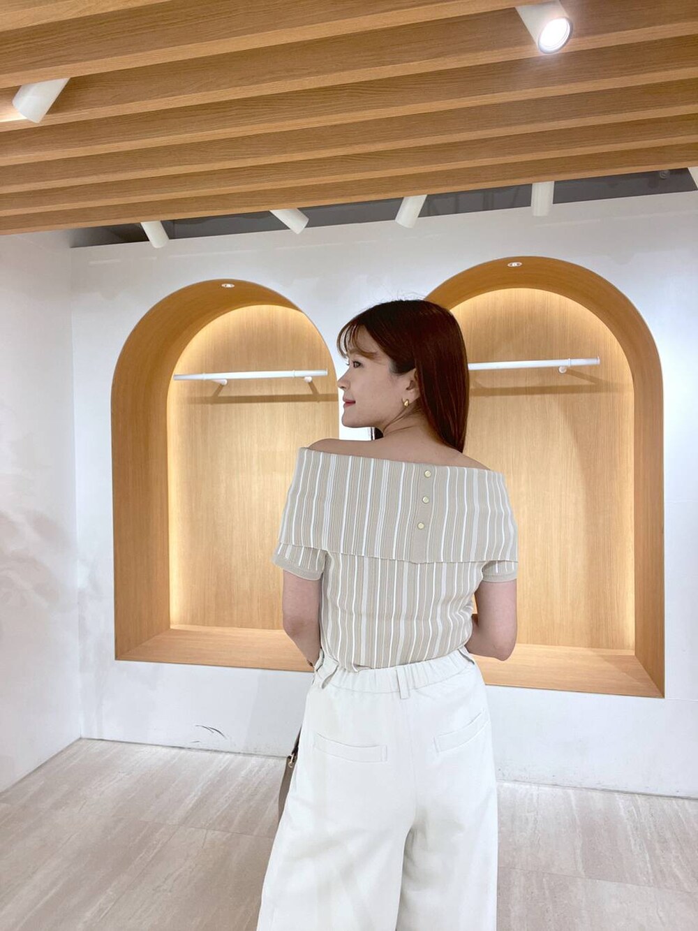 ホワイト系のサンダル、ホワイト系のスラックス、ブラウン系のハンドバッグを着用したレディースの夏コーディネートの3枚目の写真