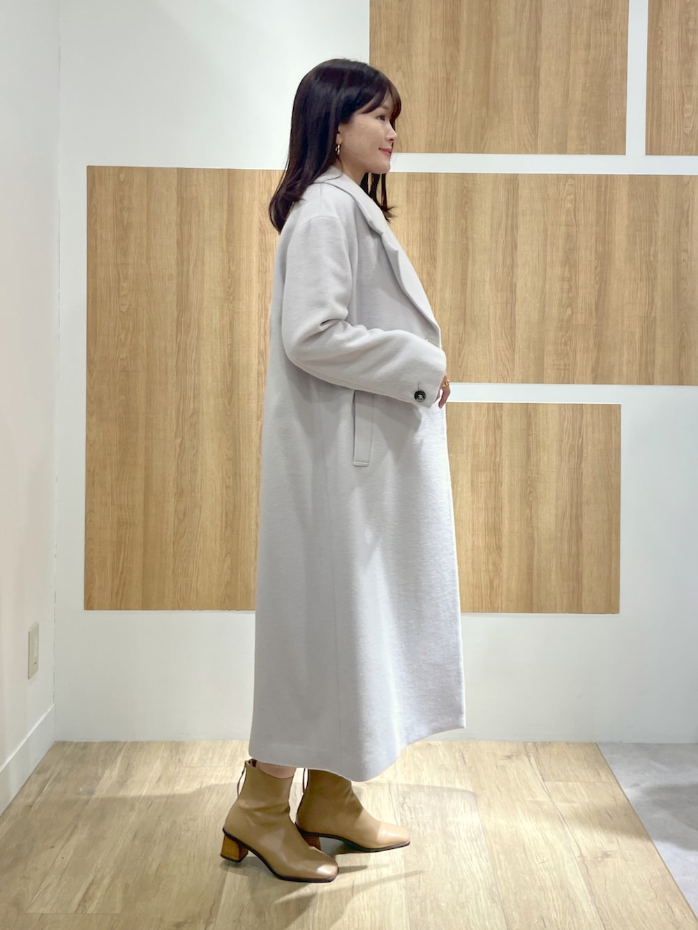 グレー系のチェスターコート、グレー系のワンピース、グリーン系のショルダーバッグを着用したレディースの冬コーディネートの2枚目の写真