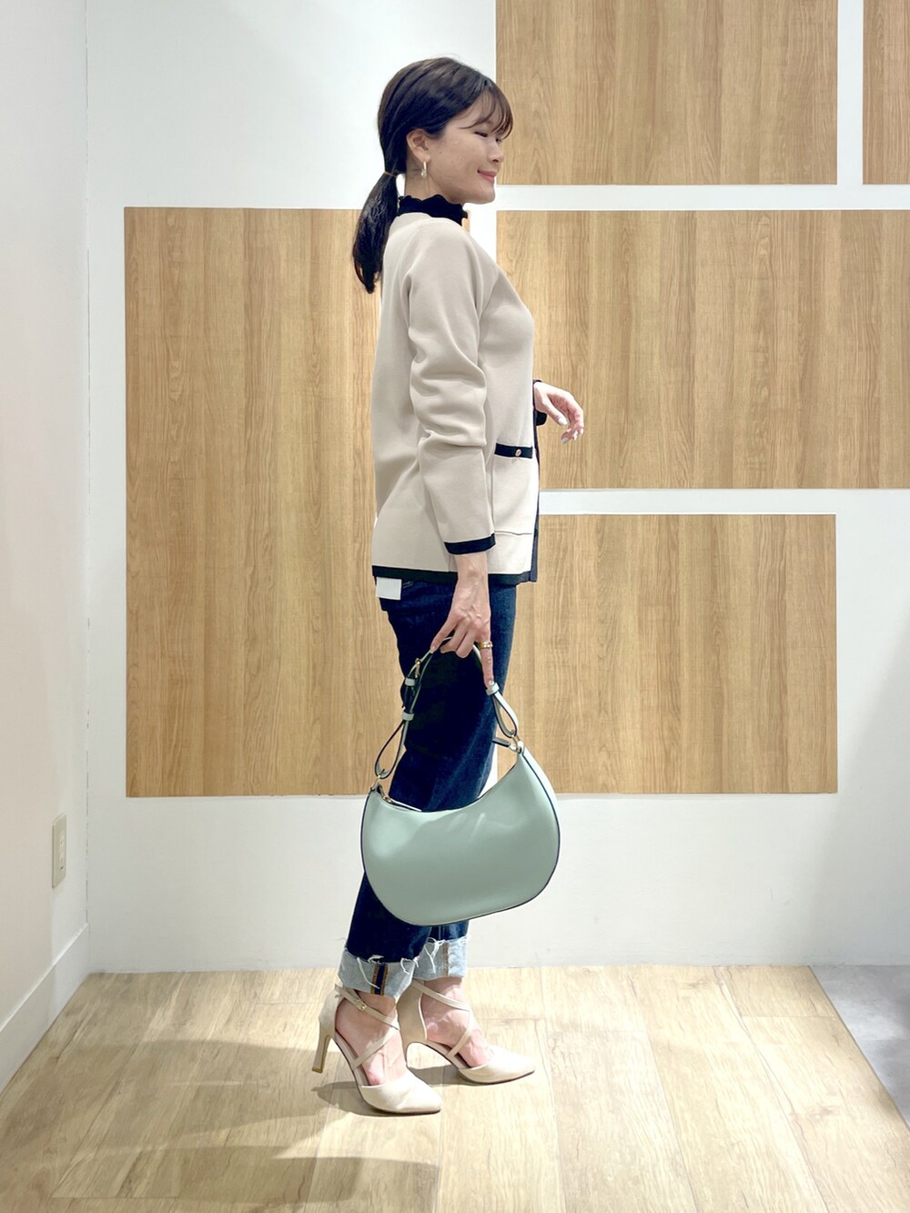 ブラック系のTシャツ/カットソー、ベージュ系のカーディガン/ボレロ、ブルー系のデニムパンツを着用したレディースの冬コーディネートの2枚目の写真