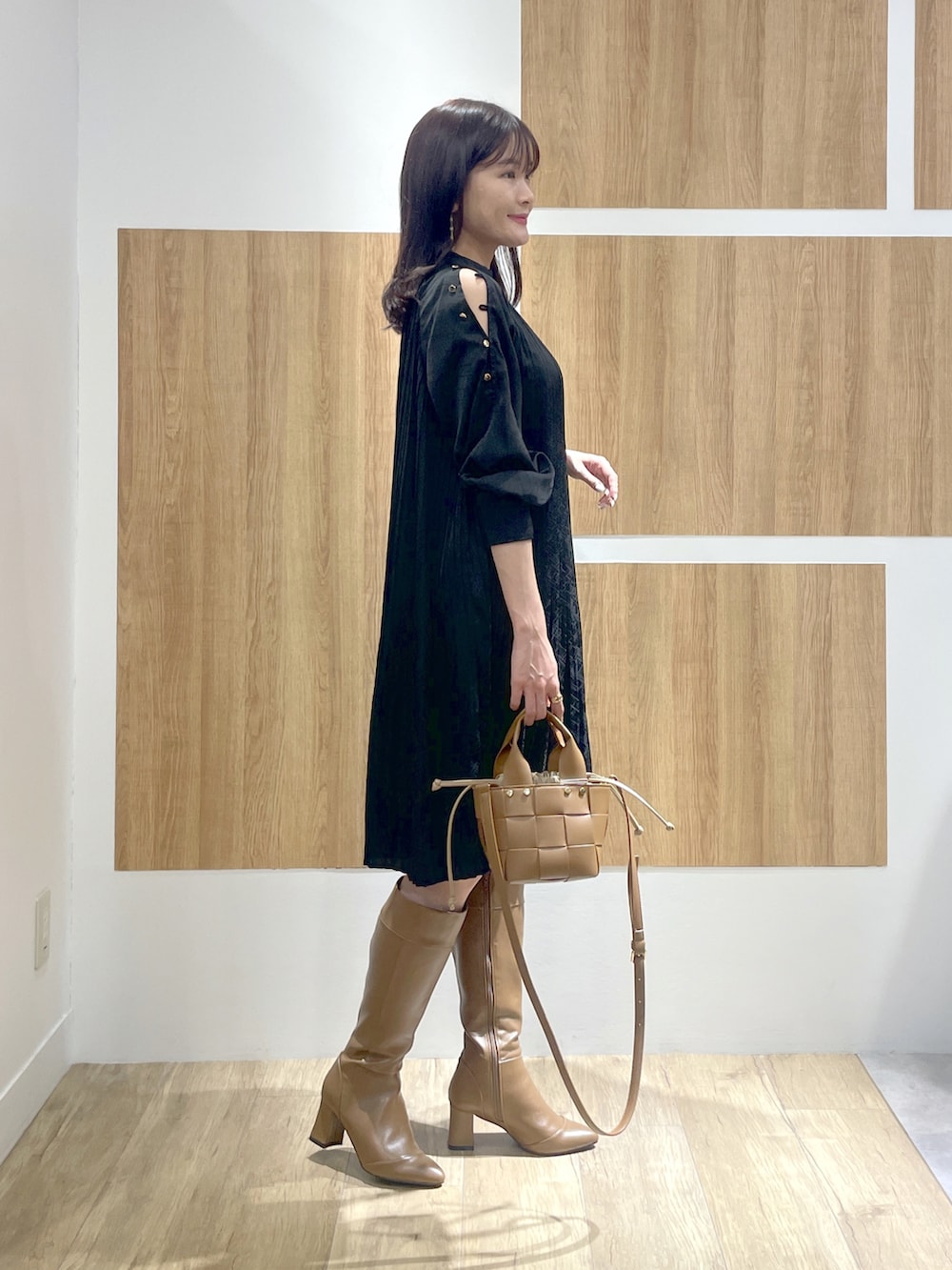 ブラック系のワンピース、ブラウン系のブーツ、ブラウン系のショルダーバッグを着用したレディースの冬コーディネートの2枚目の写真