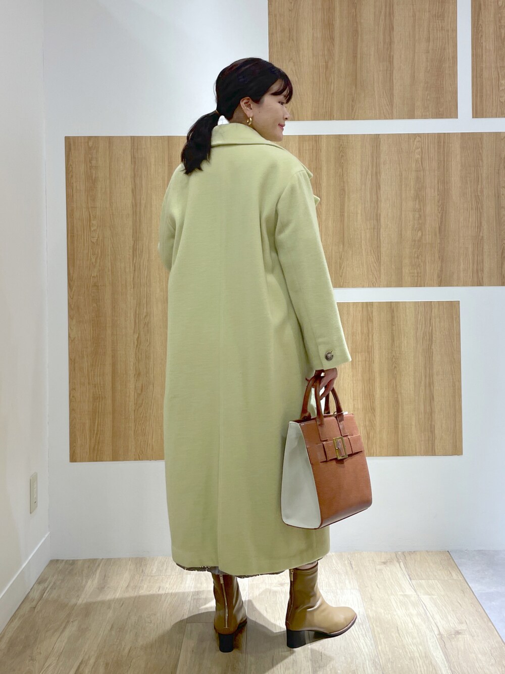 イエロー系のニット/セーター、グリーン系のチェスターコート、グレー系のスカートを着用したレディースの秋コーディネートの3枚目の写真
