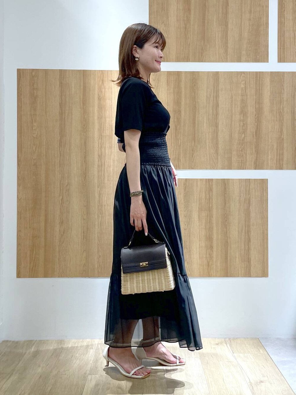 ブラウン系のかごバッグ、ホワイト系のサンダル、ブラック系のスカートを着用したレディースの夏コーディネートの3枚目の写真