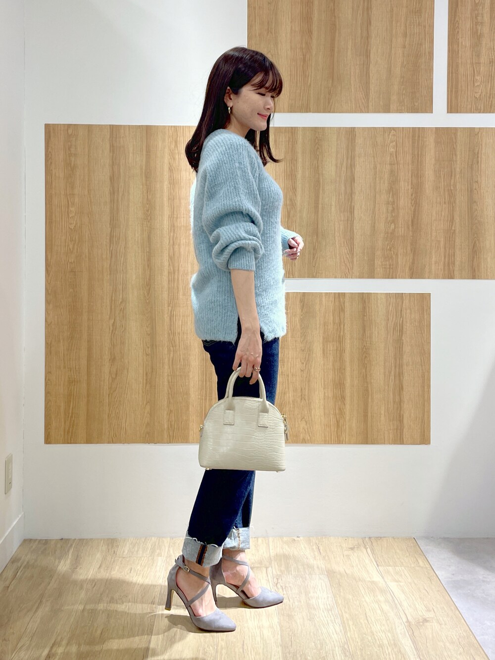 ブルー系のニット/セーター、ブルー系のデニムパンツ、ホワイト系のショルダーバッグを着用したレディースの冬コーディネートの3枚目の写真