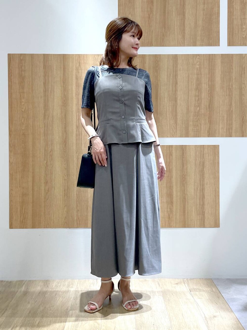 ホワイト系のサンダル、ブラック系のかごバッグ、ブラック系のTシャツ/カットソーを着用したレディースの夏コーディネートの2枚目の写真