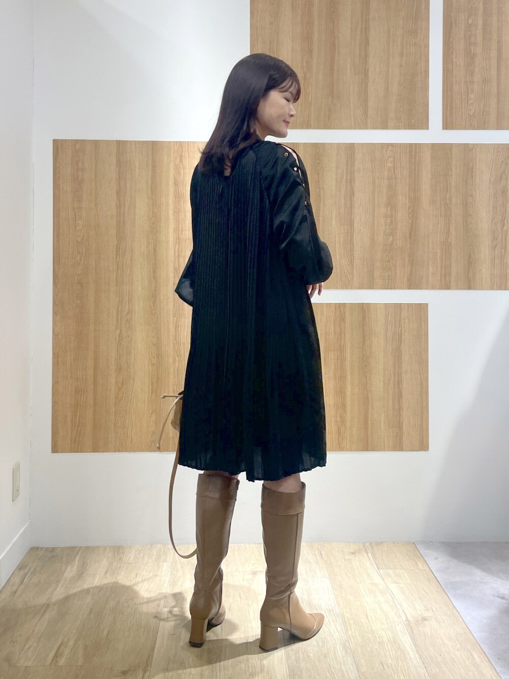 ブラック系のワンピース、ブラウン系のブーツ、ブラウン系のショルダーバッグを着用したレディースの冬コーディネートの3枚目の写真