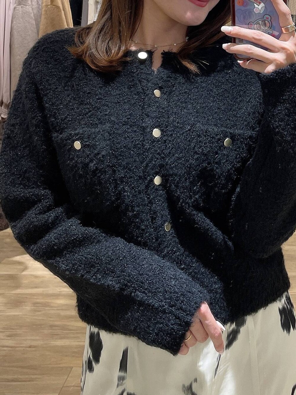 ホワイト系のスカート、ブラック系のカーディガン/ボレロ、シルバー系のネックレスを着用したレディースの冬コーディネートの2枚目の写真