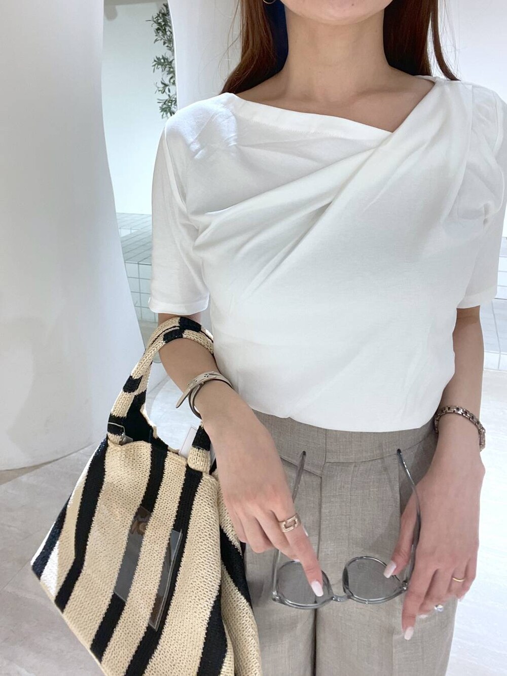 ブラック系のトートバッグ、ブラウン系のスラックス、ホワイト系のTシャツ/カットソーを着用したレディースの春コーディネートの2枚目の写真