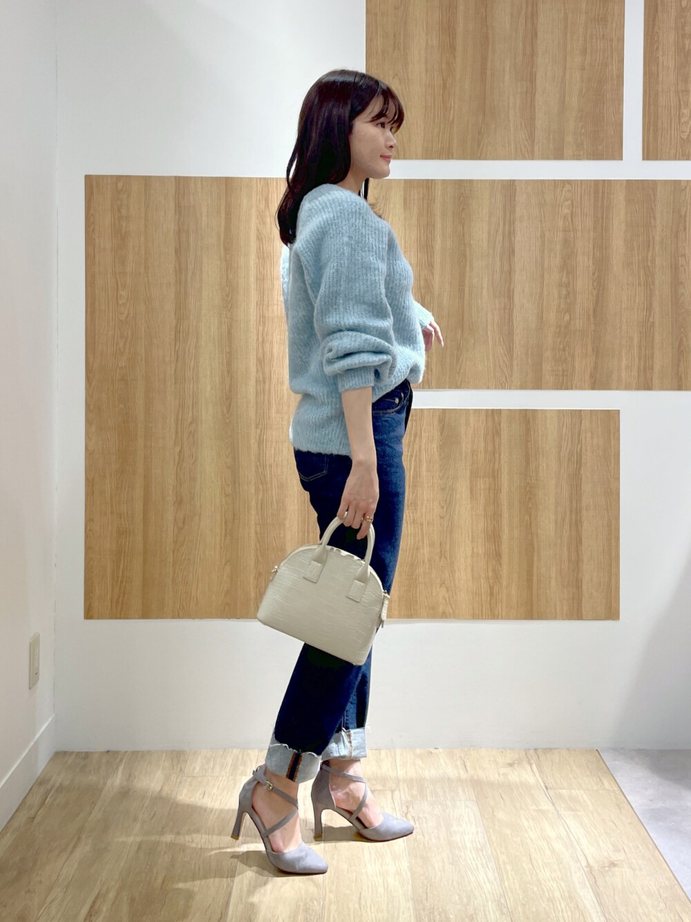 ブルー系のニット/セーター、ブルー系のデニムパンツ、ホワイト系のショルダーバッグを着用したレディースの冬コーディネートの2枚目の写真