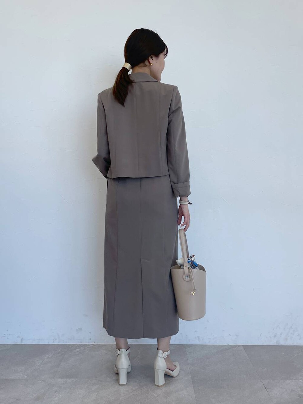 ホワイト系のパンプス、ベージュ系のショルダーバッグ、ブラウン系のテーラードジャケットを着用したレディースの春コーディネートの4枚目の写真