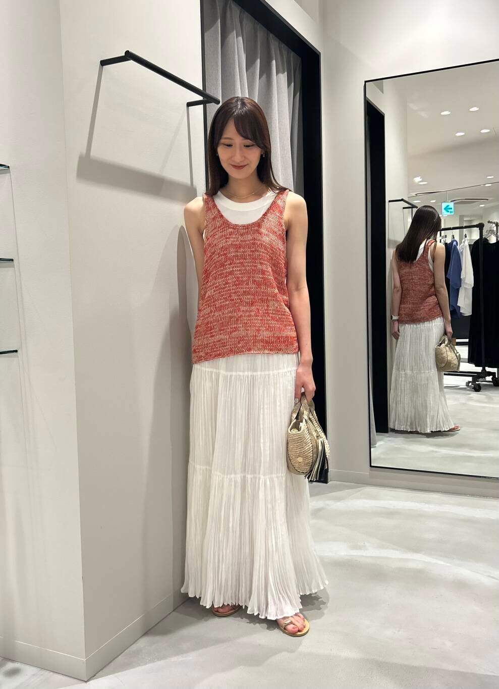 ベージュ系のかごバッグ、ホワイト系のスカート、ゴールド系のサンダルを着用したレディースの夏コーディネートの3枚目の写真
