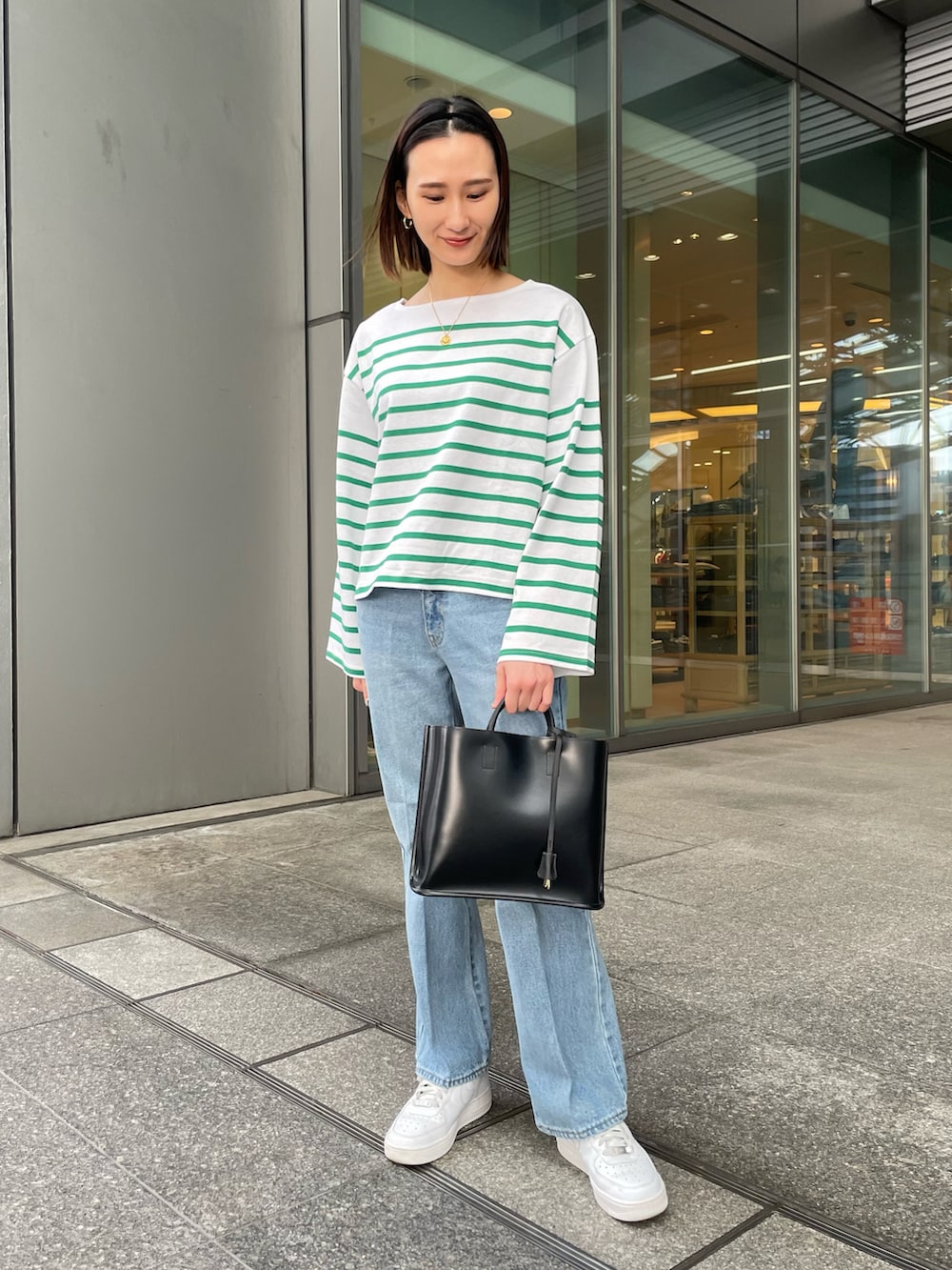 グリーン系のTシャツ/カットソー、ブルー系のデニムパンツ、ブラック系のトートバッグを着用したレディースの冬コーディネートの4枚目の写真