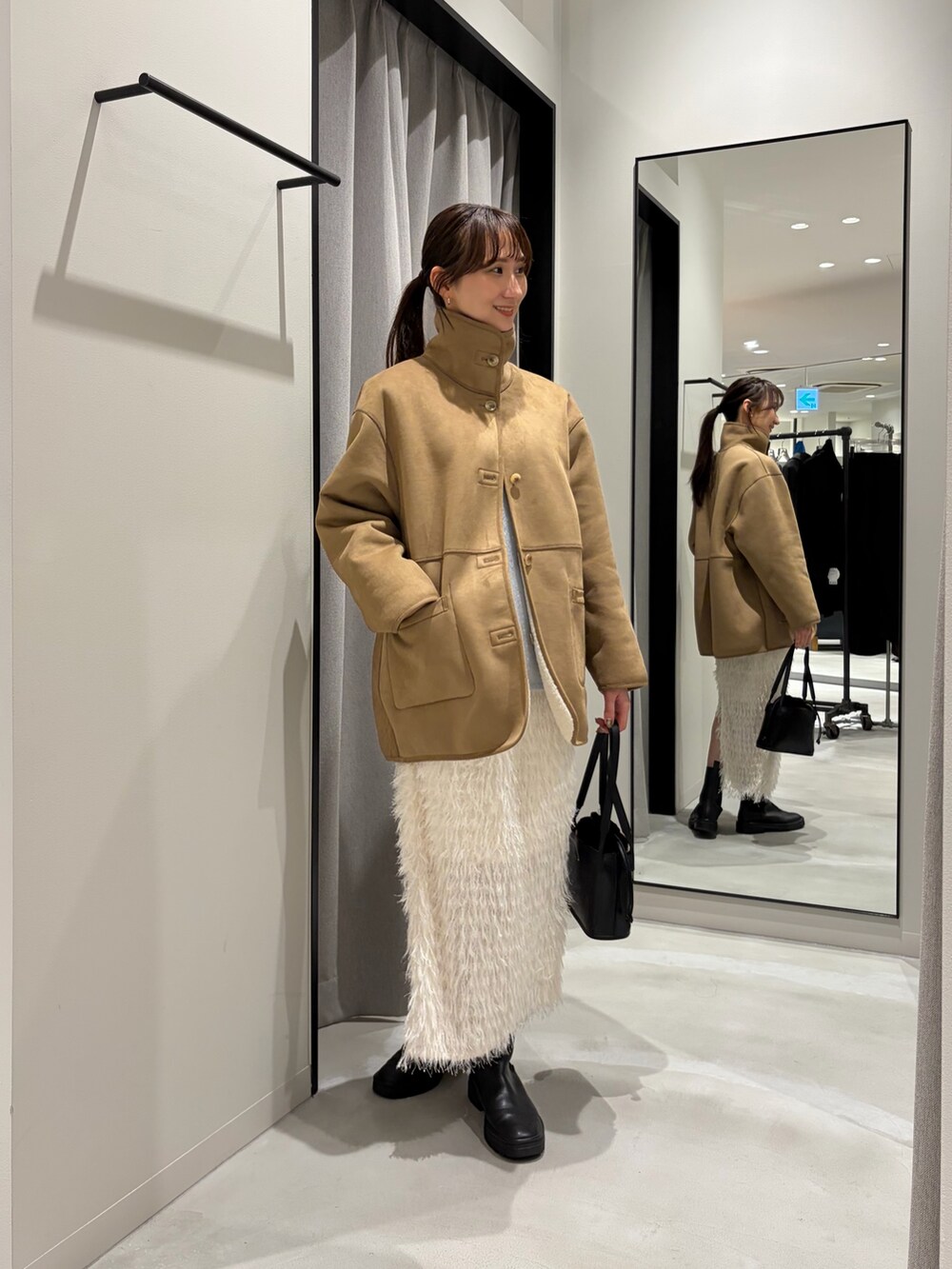 ホワイト系のムートンコート、ブルー系のニット/セーター、ホワイト系のTシャツ/カットソーを着用したレディースの冬コーディネートの5枚目の写真