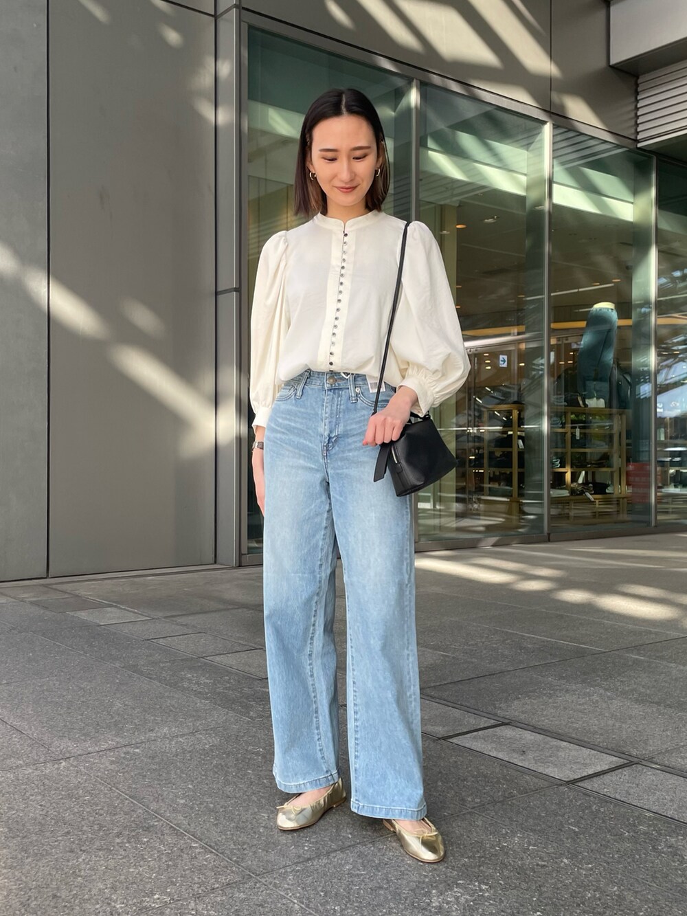 ホワイト系のシャツ/ブラウス、ブルー系のデニムパンツ、ブラック系のショルダーバッグを着用したレディースの春コーディネートの2枚目の写真