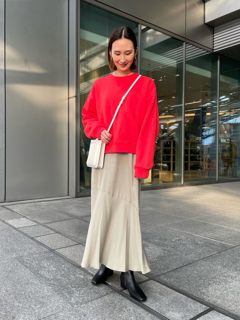 レッド系のスウェット、ベージュ系のワンピース、ブラック系のブーツを着用したレディースの冬コーディネートの2枚目の写真