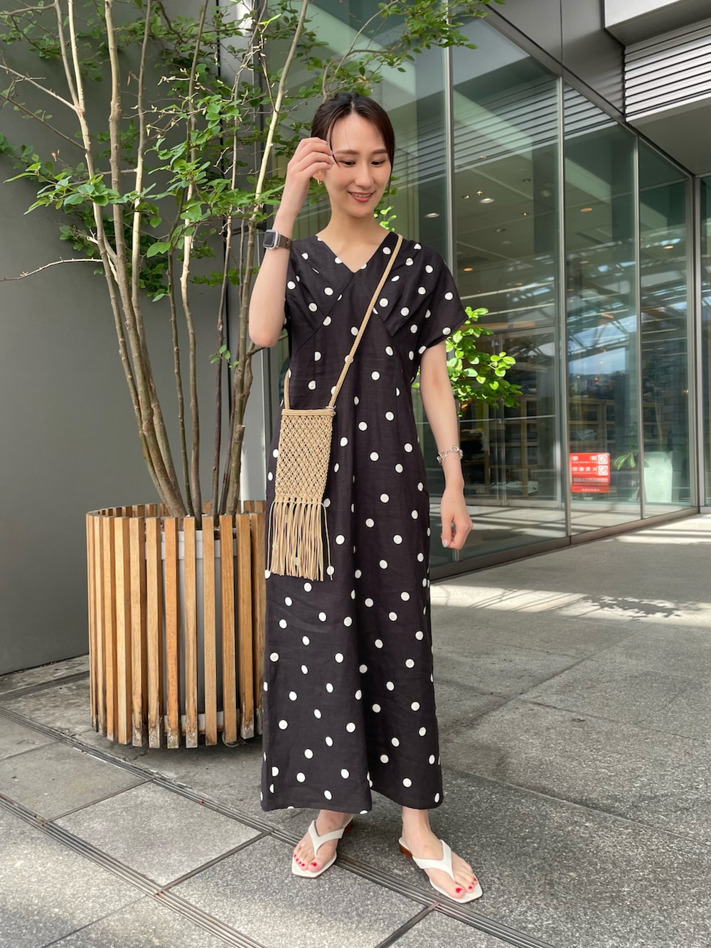 ブラック系のワンピース、ホワイト系のサンダル、シルバー系のブレスレットを着用したレディースの夏コーディネートの2枚目の写真