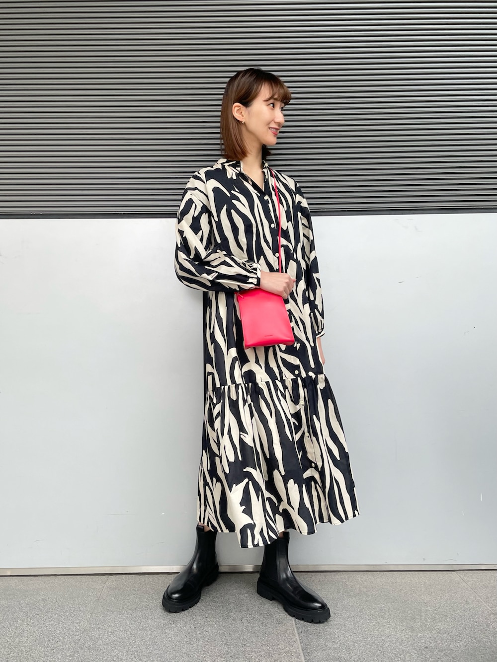 ブラック系のワンピース、ブラック系のブーツ、レッド系のショルダーバッグを着用したレディースの冬コーディネートの2枚目の写真