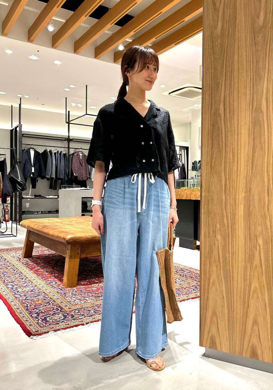 ブルー系のデニムパンツ、ブラック系のシャツ/ブラウス、ゴールド系のサンダルを着用したレディースの夏コーディネートの2枚目の写真