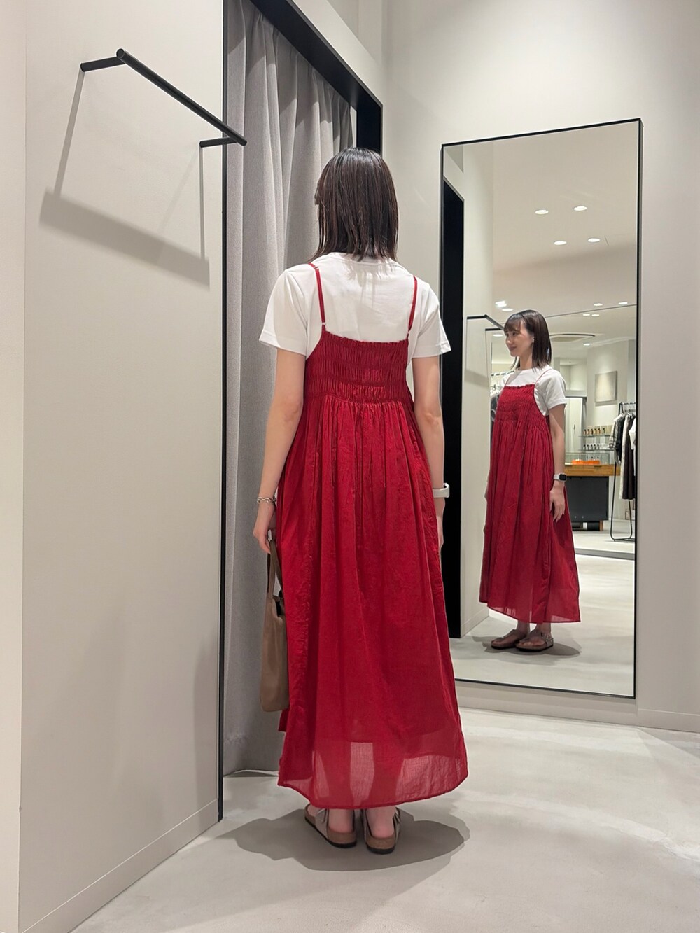 レッド系のワンピース、ホワイト系のTシャツ/カットソー、ベージュ系のサンダルを着用したレディースの春コーディネートの3枚目の写真