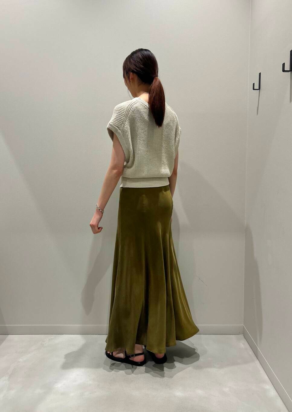 グリーン系のスカート、ブラック系のサンダル、ベージュ系のベストを着用したレディースの夏コーディネートの3枚目の写真