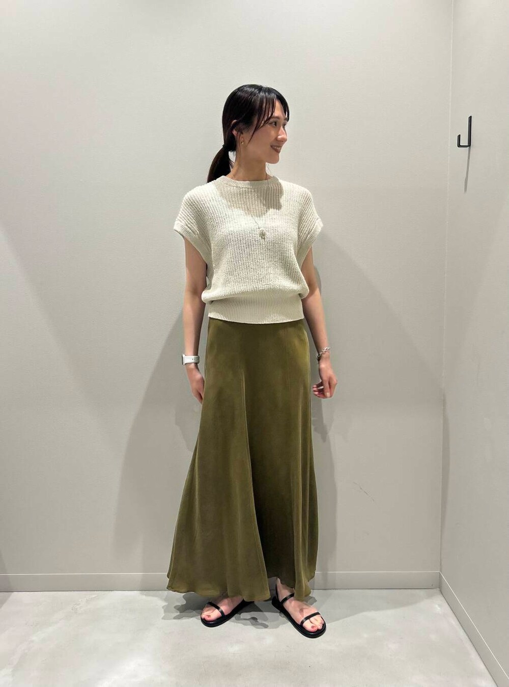 グリーン系のスカート、ブラック系のサンダル、ベージュ系のベストを着用したレディースの夏コーディネートの2枚目の写真