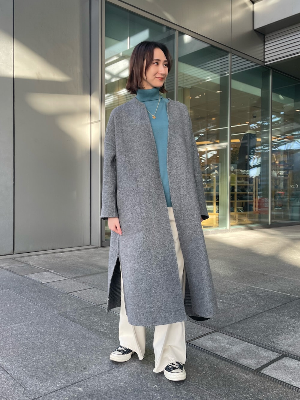 グレー系のその他アウター、ブルー系のニット/セーター、ホワイト系のデニムパンツを着用したレディースの冬コーディネートの2枚目の写真