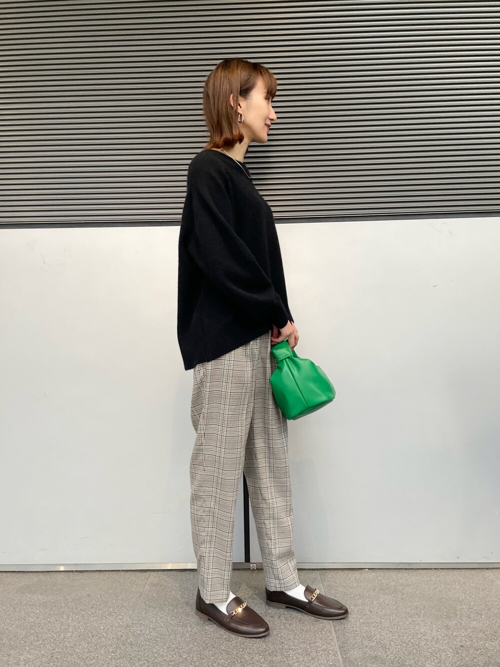 ベージュ系のその他アウター、ブラック系のニット/セーター、グリーン系のハンドバッグを着用したレディースの冬コーディネートの5枚目の写真