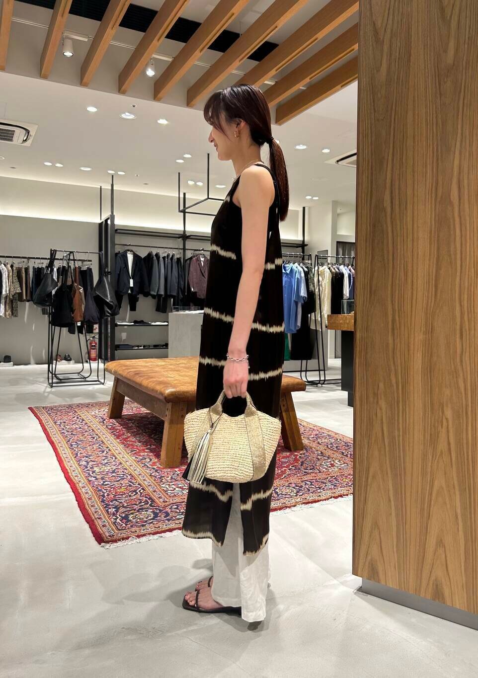 ベージュ系のかごバッグ、ブラック系のタンクトップ、ホワイト系のその他パンツを着用したレディースの夏コーディネートの3枚目の写真