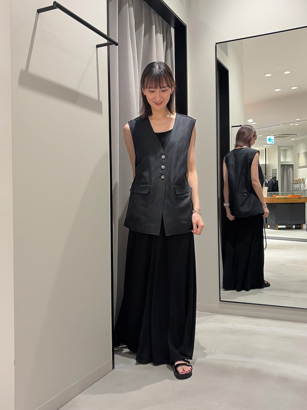 ブラック系のワンピース、ブラック系のダウンベスト、ブラック系のニット/セーターを着用したレディースの春コーディネートの2枚目の写真