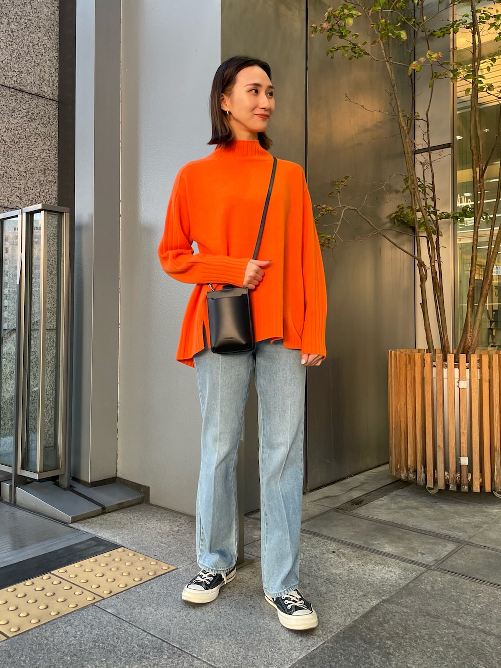 ホワイト系のダウンジャケット/コート、オレンジ系のニット/セーター、ブルー系のデニムパンツを着用したレディースの秋コーディネートの2枚目の写真