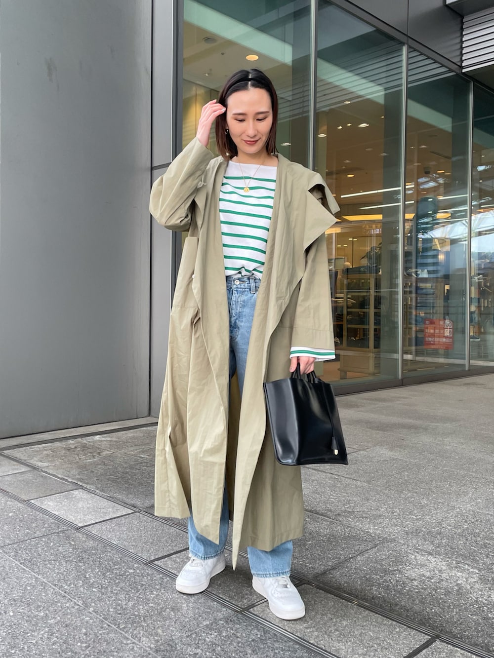 グリーン系のTシャツ/カットソー、ブルー系のデニムパンツ、ブラック系のトートバッグを着用したレディースの冬コーディネートの2枚目の写真