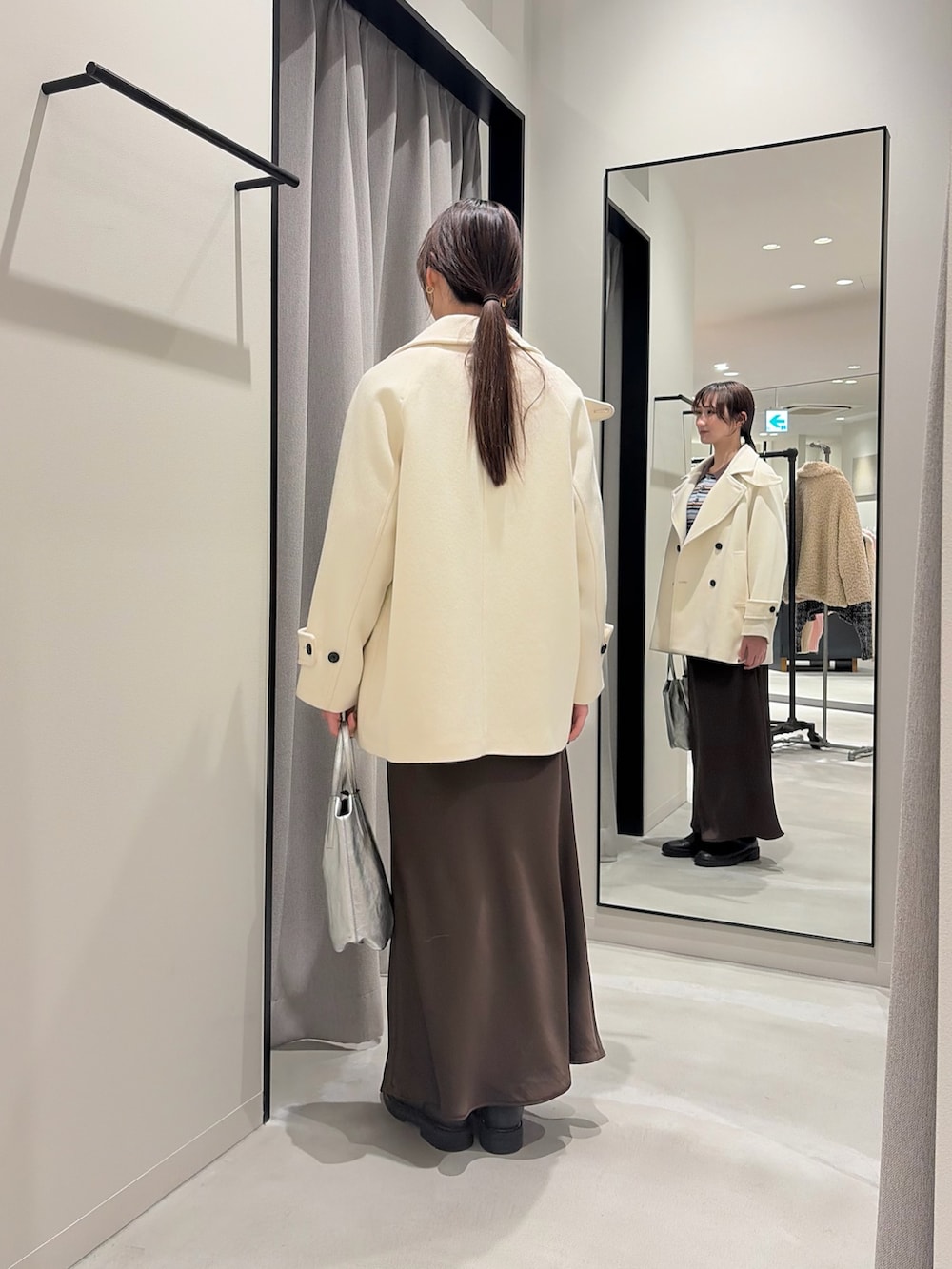 その他のニット/セーター、ホワイト系のピーコート、ブラウン系のスカートを着用したレディースの冬コーディネートの2枚目の写真