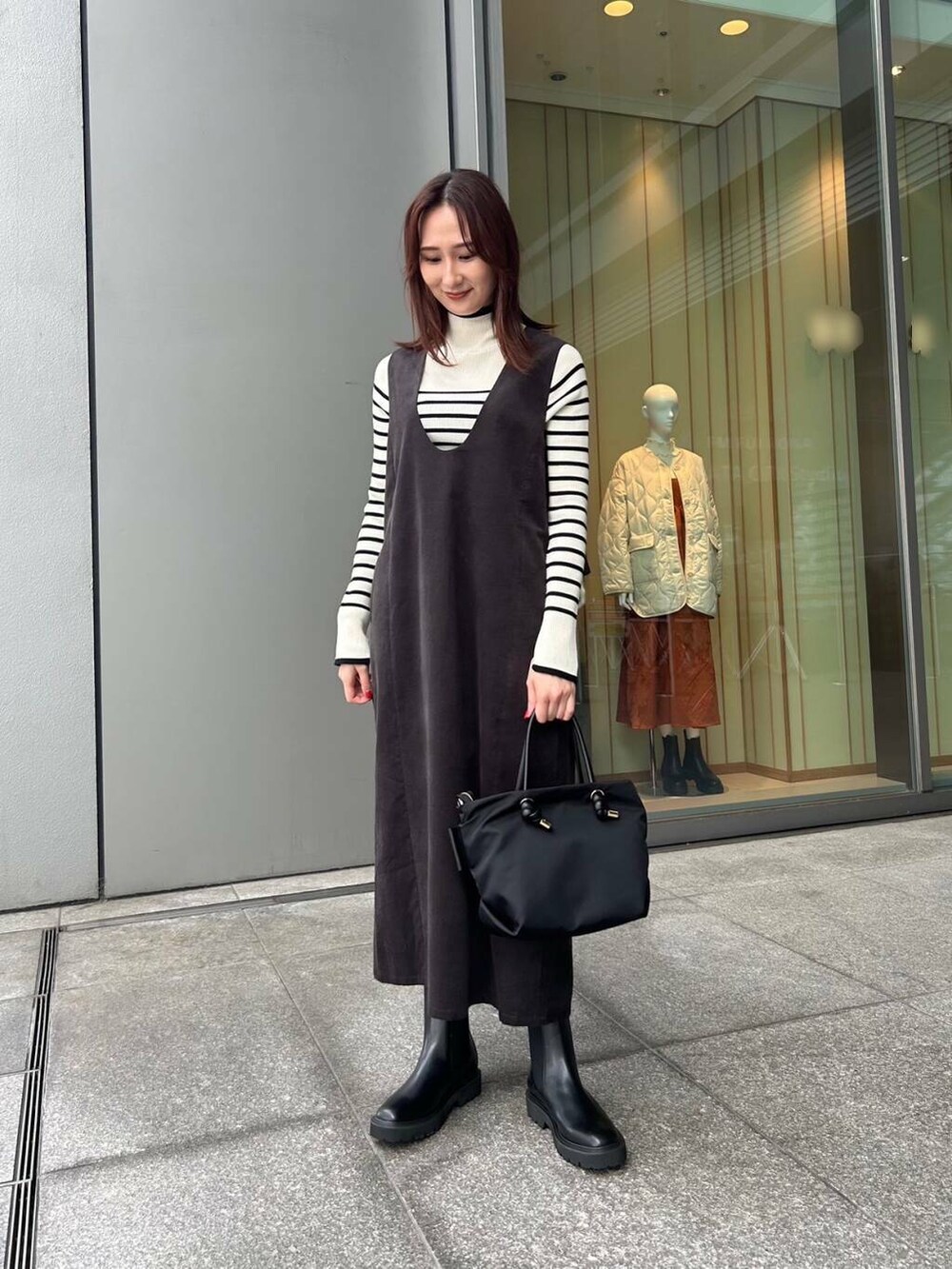 ブラック系のハンドバッグ、ホワイト系のニット/セーター、ブラック系のブーツを着用したレディースの秋コーディネートの2枚目の写真