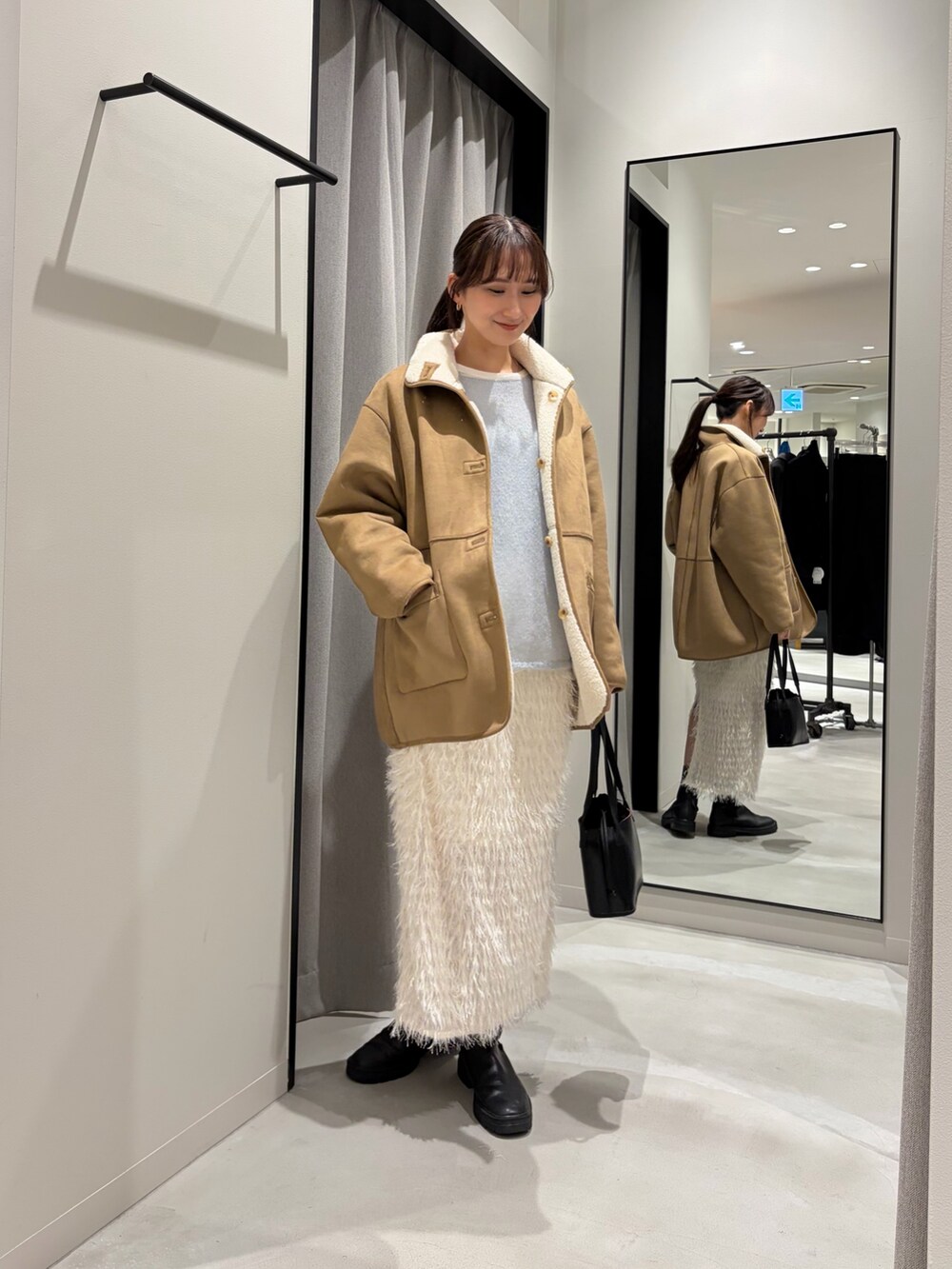 ホワイト系のムートンコート、ブルー系のニット/セーター、ホワイト系のTシャツ/カットソーを着用したレディースの冬コーディネートの4枚目の写真