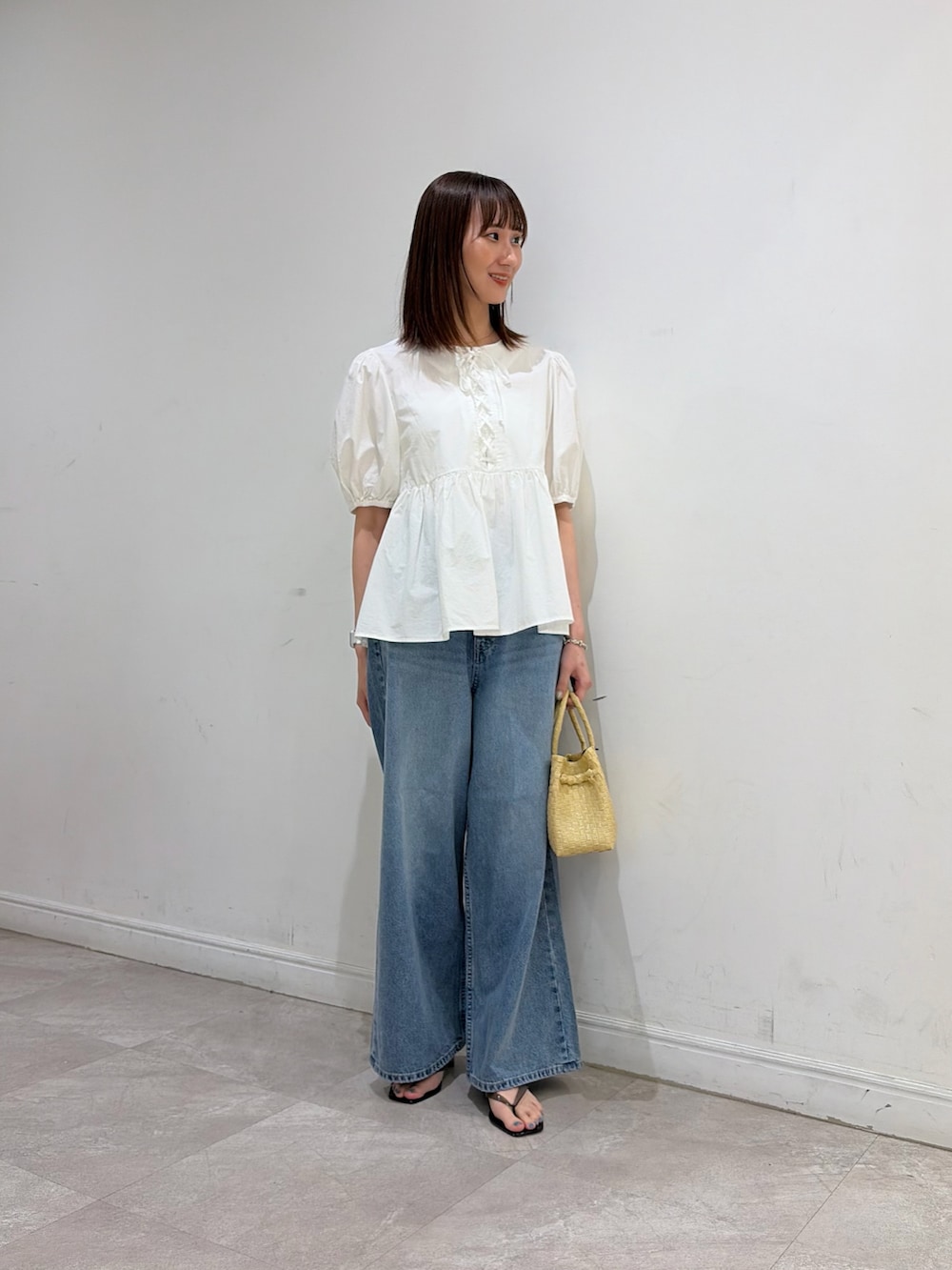ホワイト系のシャツ/ブラウス、ブルー系のデニムパンツ、ベージュ系のトートバッグを着用したレディースの夏コーディネートの2枚目の写真